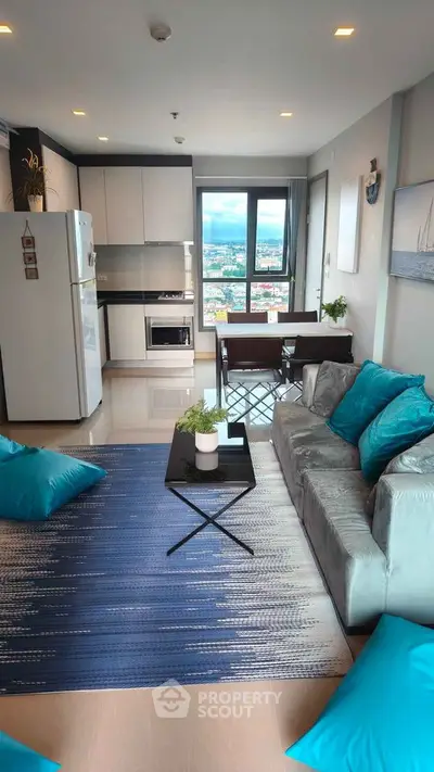 Modern living room with city view, stylish decor, and open kitchen layout.