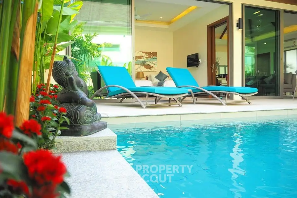 Luxurious poolside view with modern lounge chairs and lush greenery in a serene setting.
