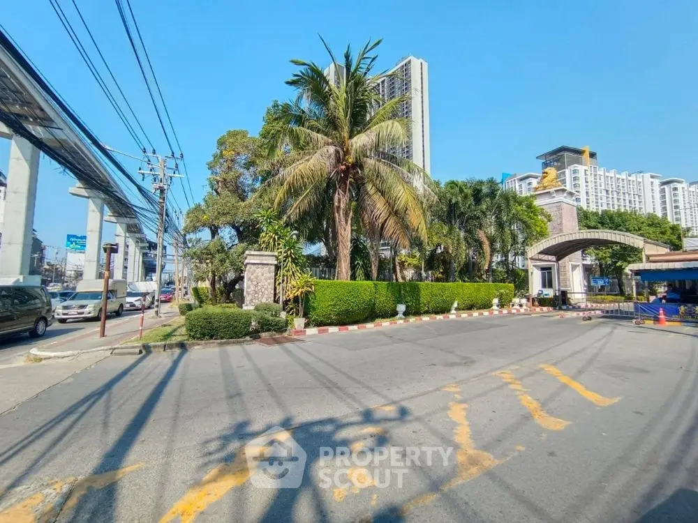 Luxurious gated community entrance with lush greenery and modern high-rise buildings.