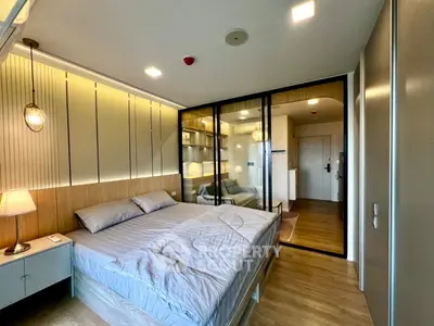 Modern bedroom with stylish lighting and glass partition, featuring cozy bed and wooden flooring.