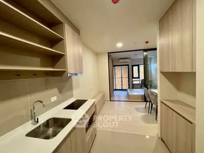 Modern kitchen with sleek cabinetry and open layout leading to dining area.
