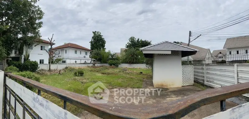 Spacious residential plot with lush greenery and charming gazebo, ideal for custom home building.