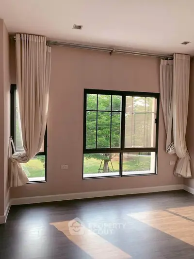 Spacious corner unit with large windows and elegant curtains, offering a serene garden view.