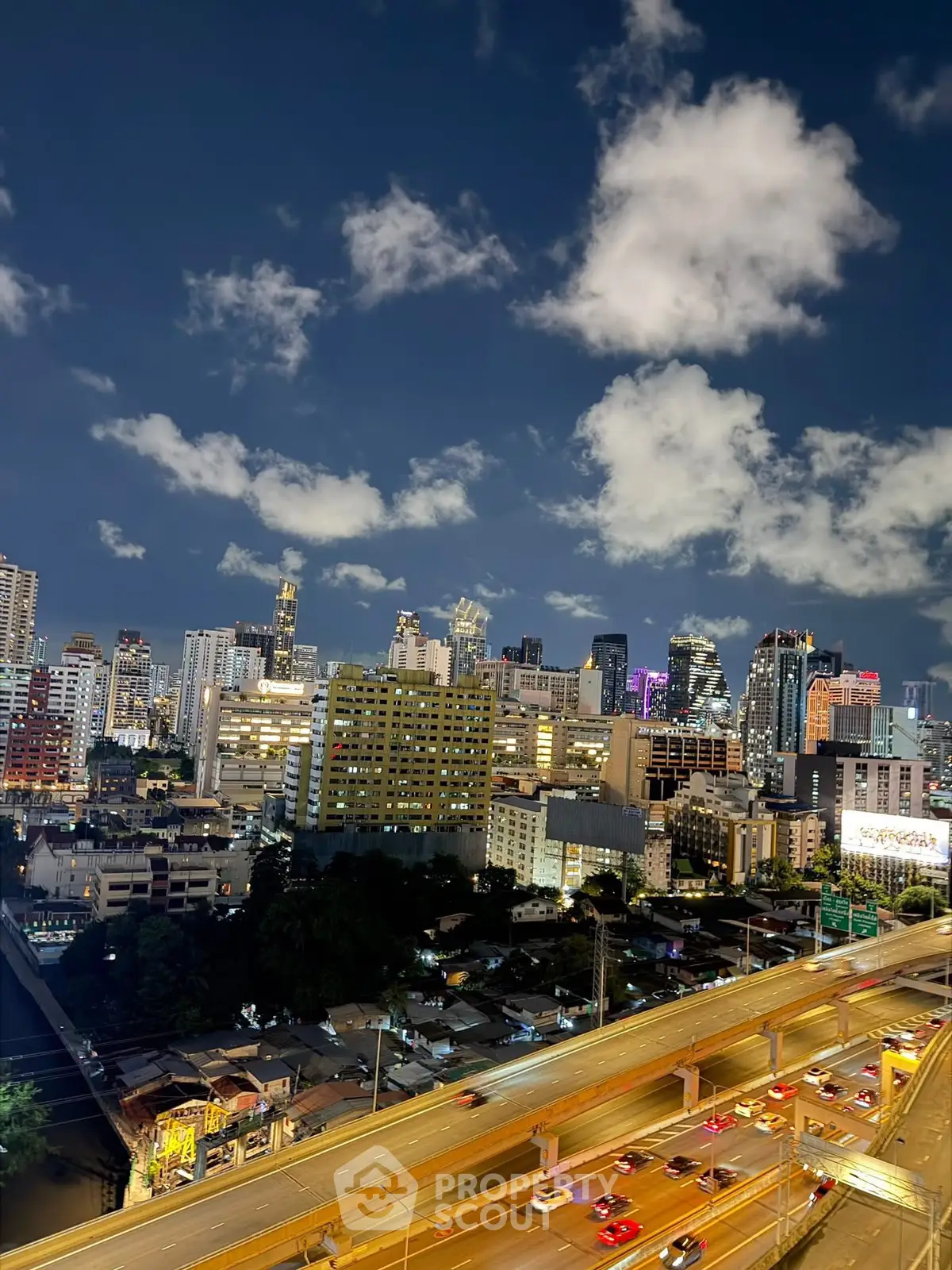 Stunning city skyline view with illuminated skyscrapers and bustling highway at night.