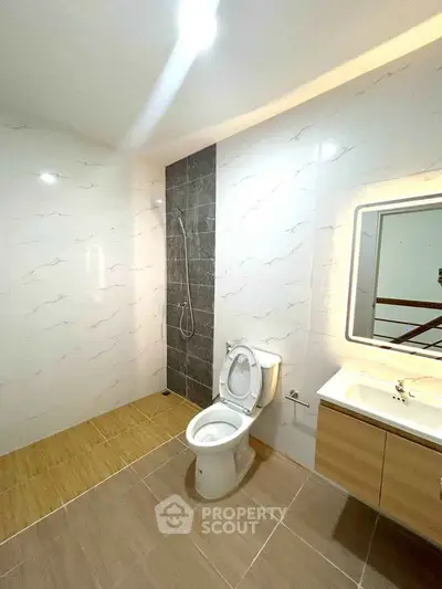 Modern bathroom with sleek design, featuring a toilet, shower, and illuminated mirror.