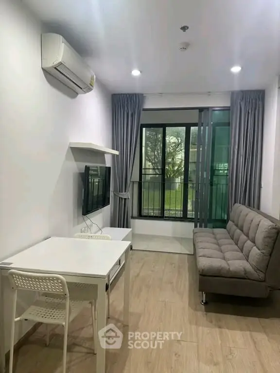 Modern living room with balcony, featuring sleek furniture and natural light.