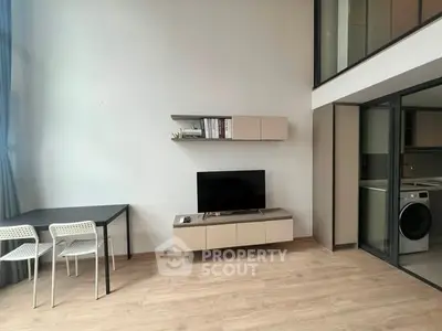 Modern living room with high ceiling and minimalist decor, featuring a TV and dining area.