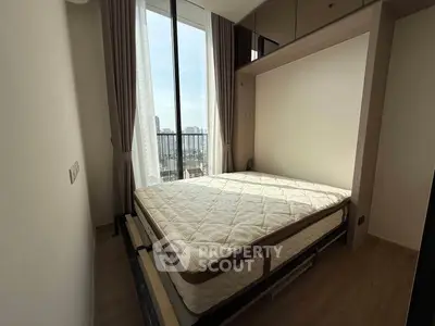 Modern bedroom with large window and city view, featuring a comfortable bed and elegant decor.