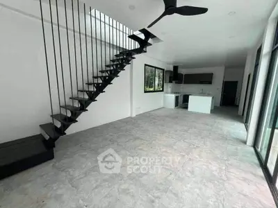 Modern open-plan living room with sleek staircase and kitchen in minimalist design.