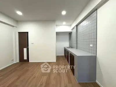 Modern kitchen with sleek design and wooden flooring, featuring a minimalist aesthetic.