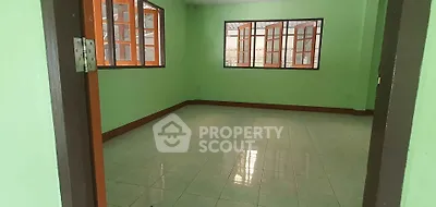 Spacious room with green walls and large windows offering ample natural light.