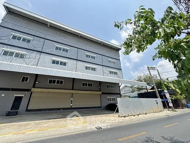 Modern industrial building exterior with large windows and loading dock on a sunny day.