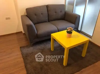 Cozy living room with modern gray sofa and vibrant yellow coffee table on a plush rug.