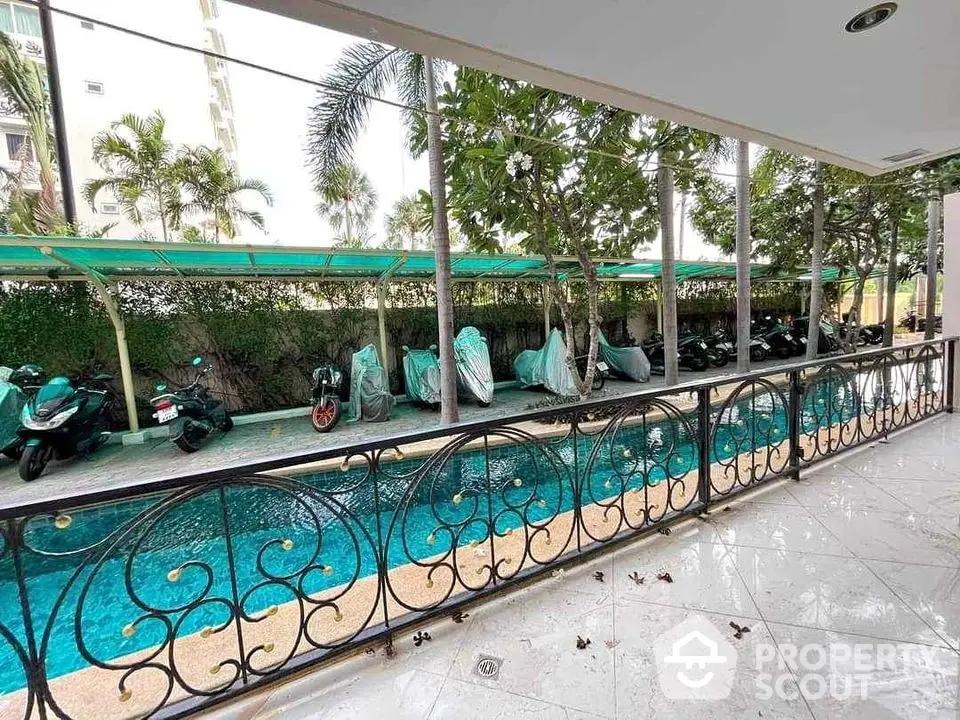 Charming poolside view with lush greenery and covered parking area.