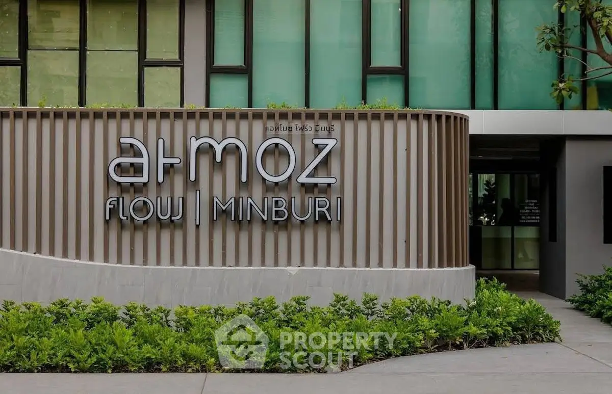 Modern building entrance with sleek design and lush greenery at Atmoz Flow Minburi.