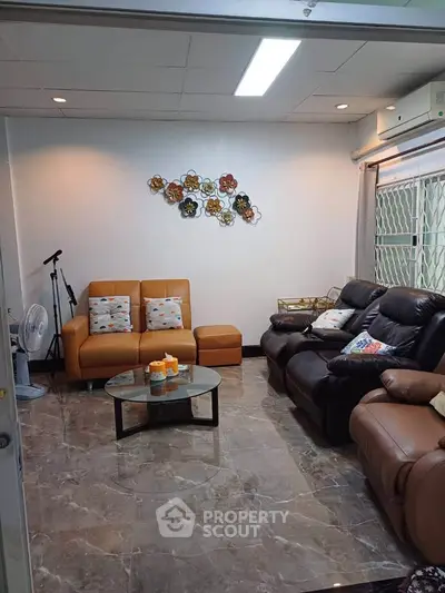 Cozy living room with stylish leather sofas and decorative wall art, perfect for relaxation.