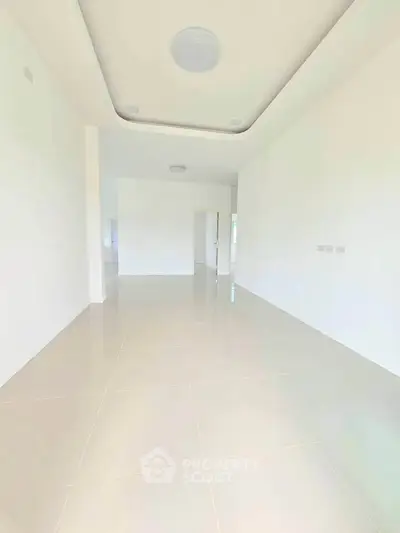 Spacious and bright empty room with modern tile flooring and high ceiling, perfect for customization.