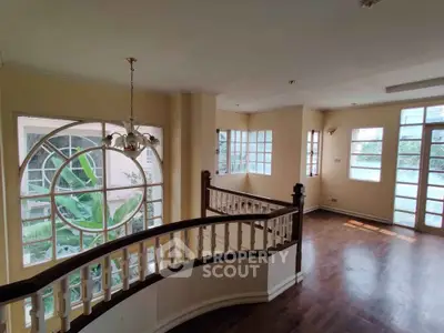 Spacious living room with elegant staircase and large windows offering natural light