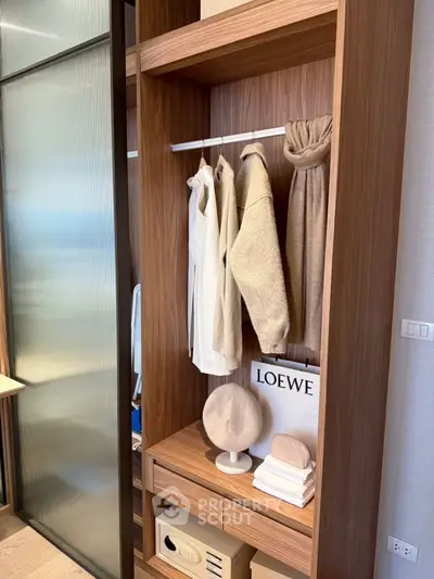 Modern wooden wardrobe with stylish clothes and accessories in a luxury apartment.