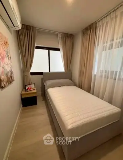 Cozy bedroom with single bed and elegant curtains, perfect for relaxation.