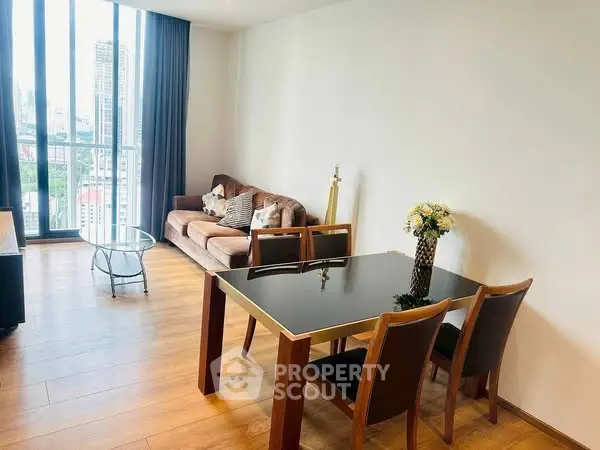 Modern living room with large windows and stylish furniture in a high-rise apartment.