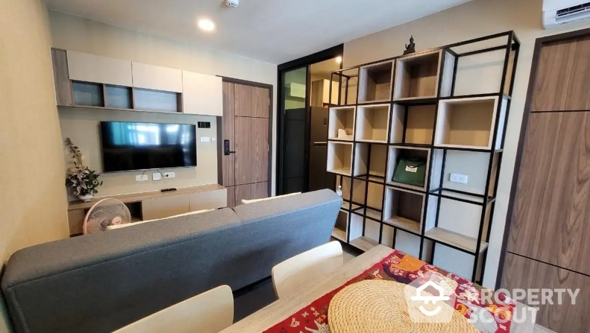 Modern living room with stylish shelving and wall-mounted TV in cozy apartment.