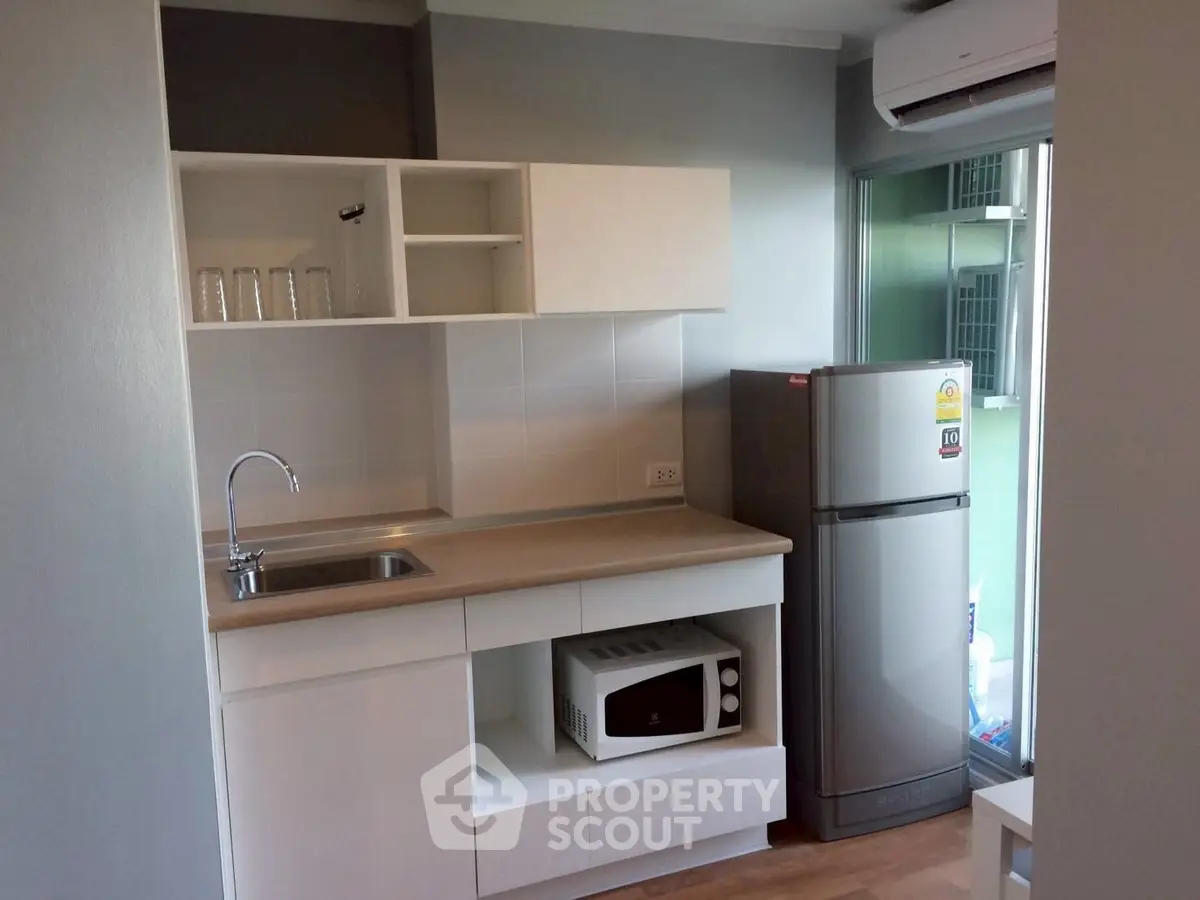 Modern compact kitchen with sleek cabinetry and stainless steel appliances in a cozy apartment.
