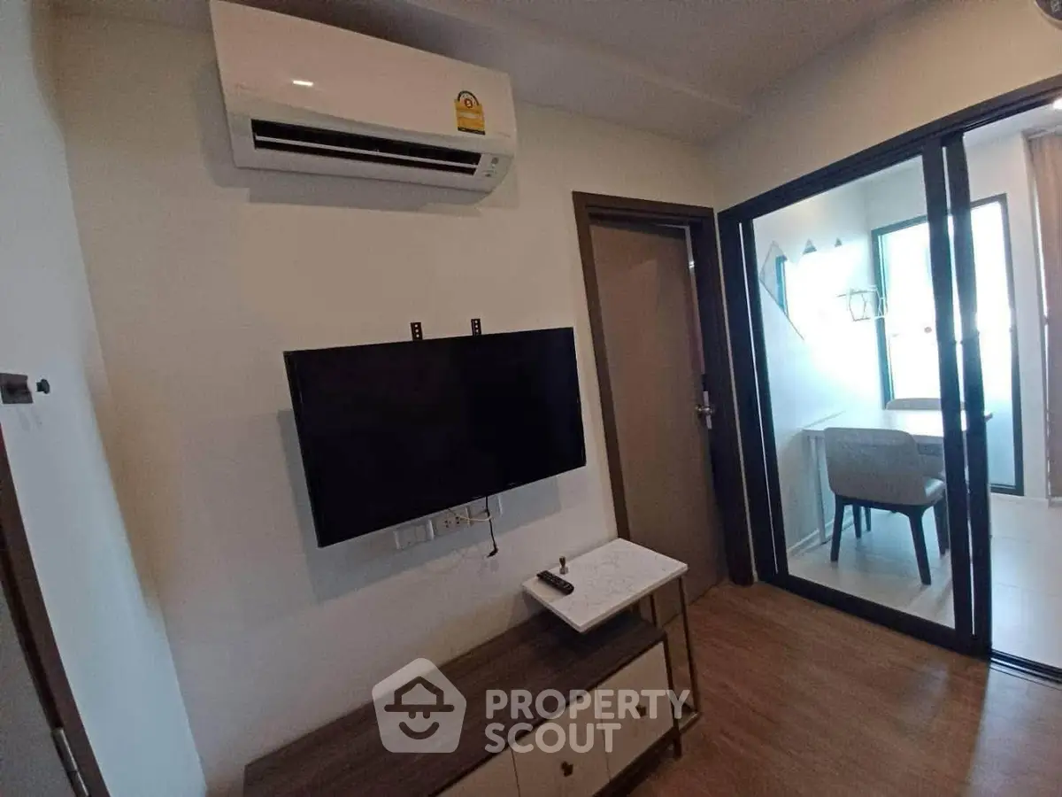 Modern living room with air conditioning and TV, featuring a stylish workspace in a bright corner.
