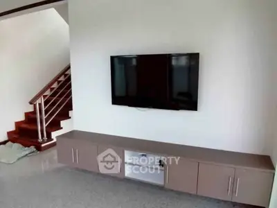 Modern living room with sleek TV setup and stylish staircase