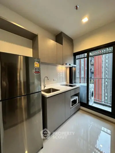 Modern kitchen with sleek appliances and balcony view in urban apartment