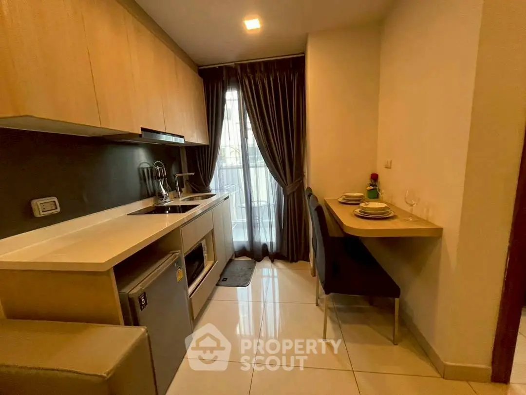 Modern kitchen with sleek cabinetry and cozy dining area in a compact apartment setting.