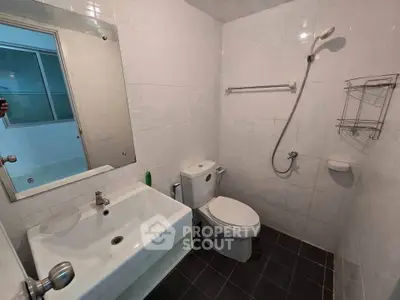 Modern bathroom with sleek fixtures and minimalist design, featuring a shower and a large mirror.