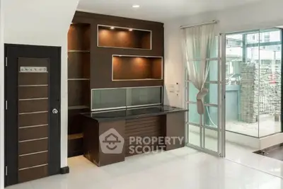 Modern living room with sleek built-in shelving and large glass doors opening to a patio.