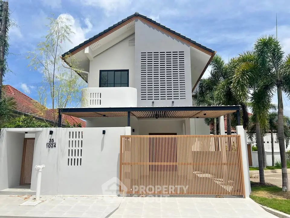 Modern two-story house with sleek design and spacious outdoor area, featuring a stylish wooden gate and lush greenery.