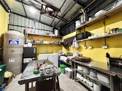 Spacious industrial-style kitchen with stainless steel counters and ample shelving.