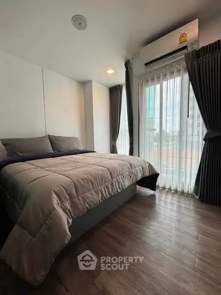 Modern bedroom with large window and stylish decor in urban apartment.