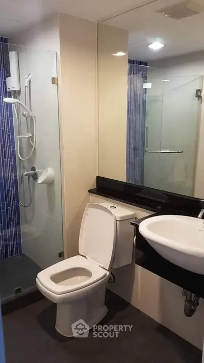 Modern bathroom with glass shower and sleek fixtures in contemporary apartment.