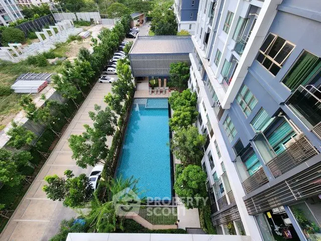 Stunning aerial view of modern apartment complex with a sparkling pool and lush greenery, perfect for urban living.