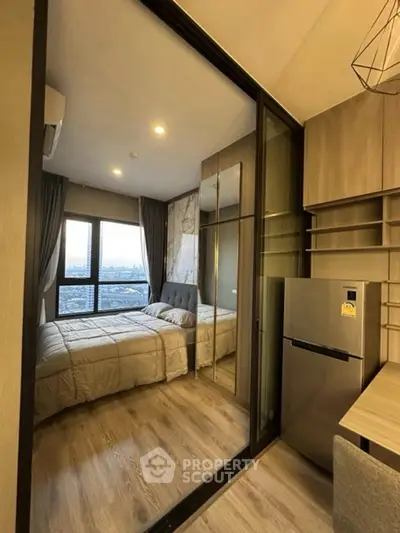 Modern bedroom with glass partition, cozy bed, and city view, featuring sleek wooden flooring and built-in storage.