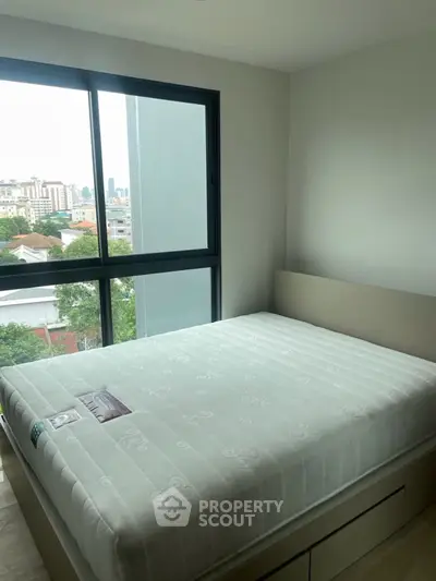 Modern bedroom with large window offering city view, featuring a comfortable bed and sleek design.