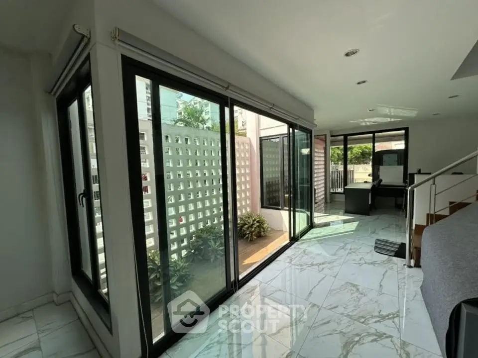 Spacious modern living room with large windows and marble flooring