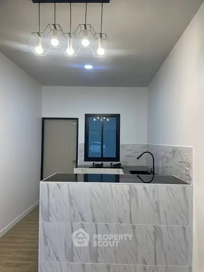 Modern kitchen with sleek marble island and stylish lighting