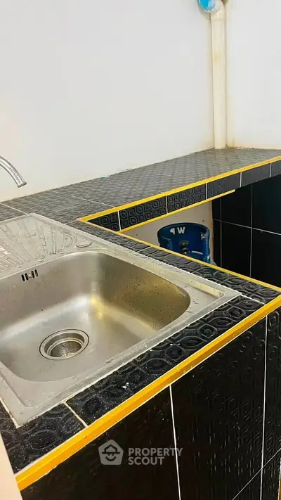 Compact kitchen sink with black and yellow tiled countertop