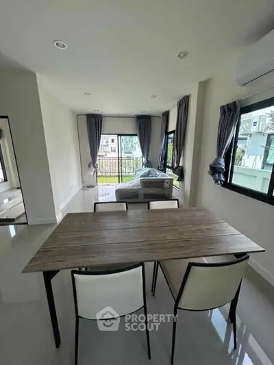 Modern dining area with large windows and balcony view in a bright apartment.
