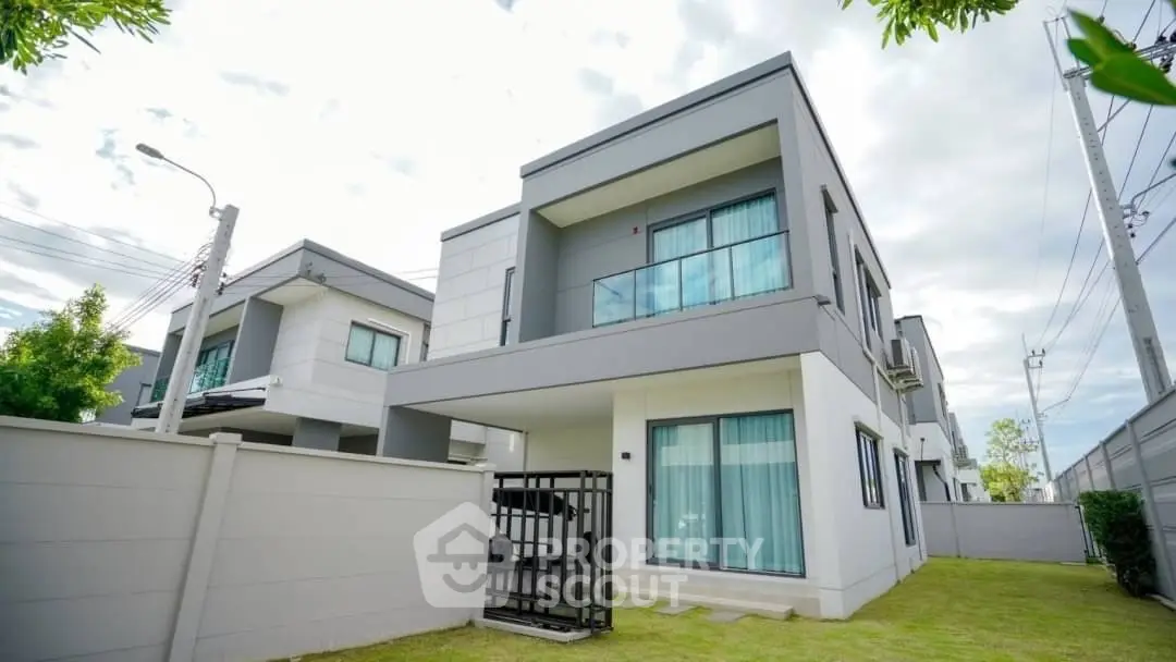 Modern two-story house with sleek design and spacious lawn in a serene neighborhood.