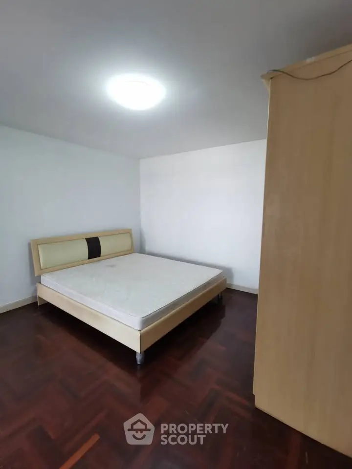 Spacious bedroom with wooden flooring and modern bed frame, ideal for comfort and style.