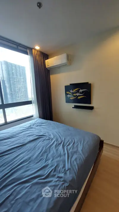 Modern bedroom with large window and city view, featuring air conditioning and stylish decor.