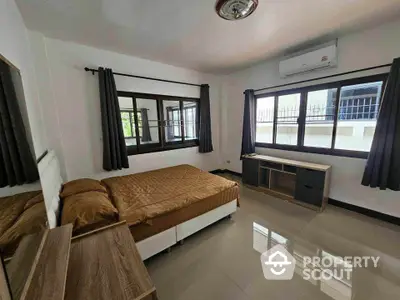 Spacious bedroom with modern furnishings and large windows for natural light.