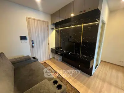 Modern living room with sleek black entertainment unit and cozy seating in stylish apartment.