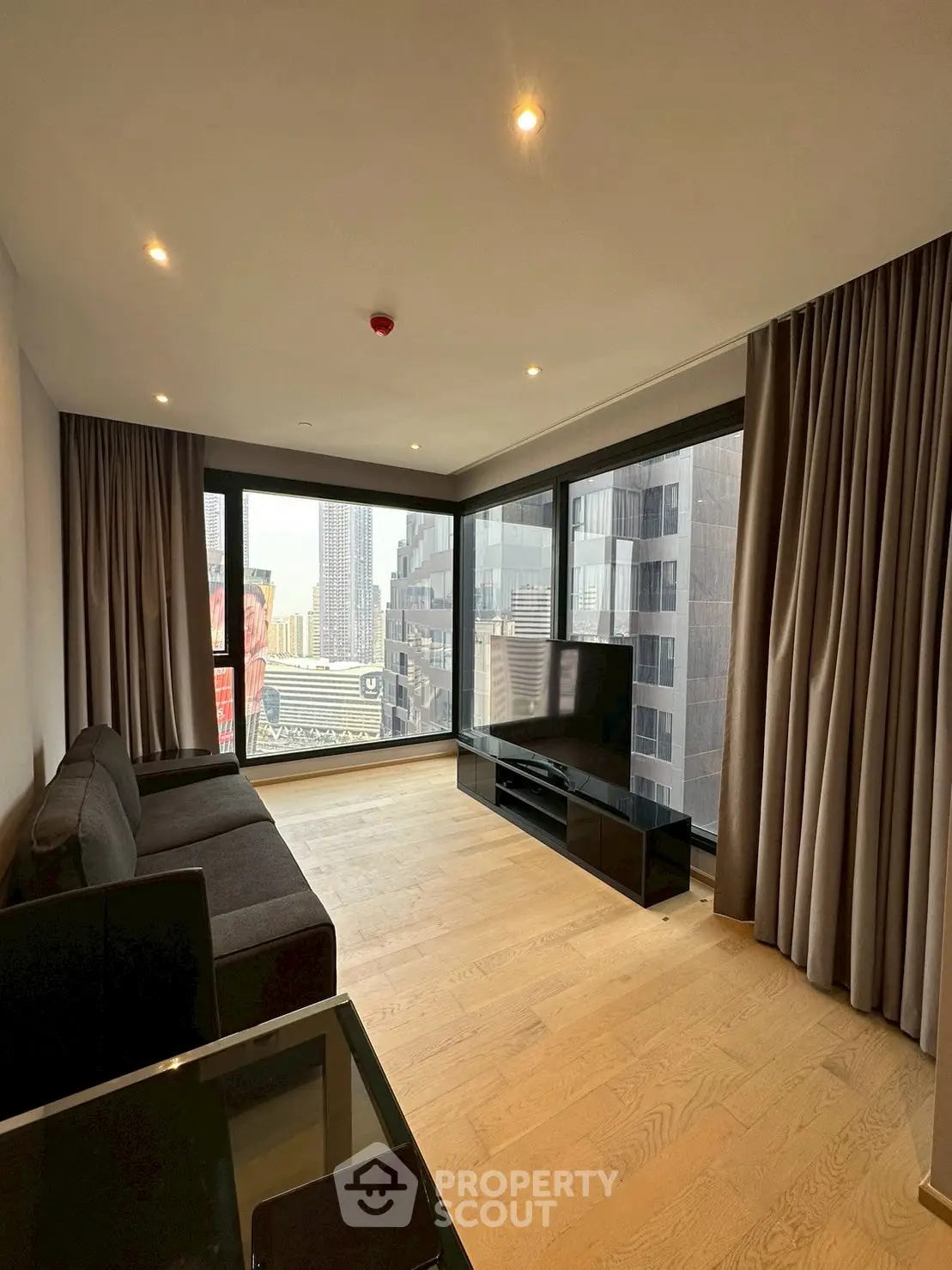 Spacious modern living room with floor-to-ceiling windows and stunning city view.